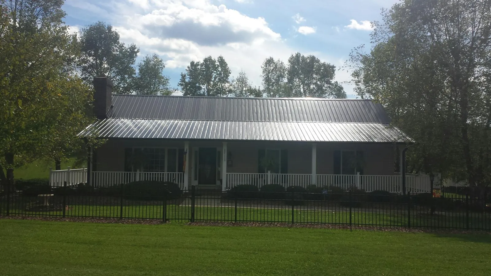 Gray metal roof on a brick ranch with a full width front porch — Gutter Guard Installation work by our crew in Tryon