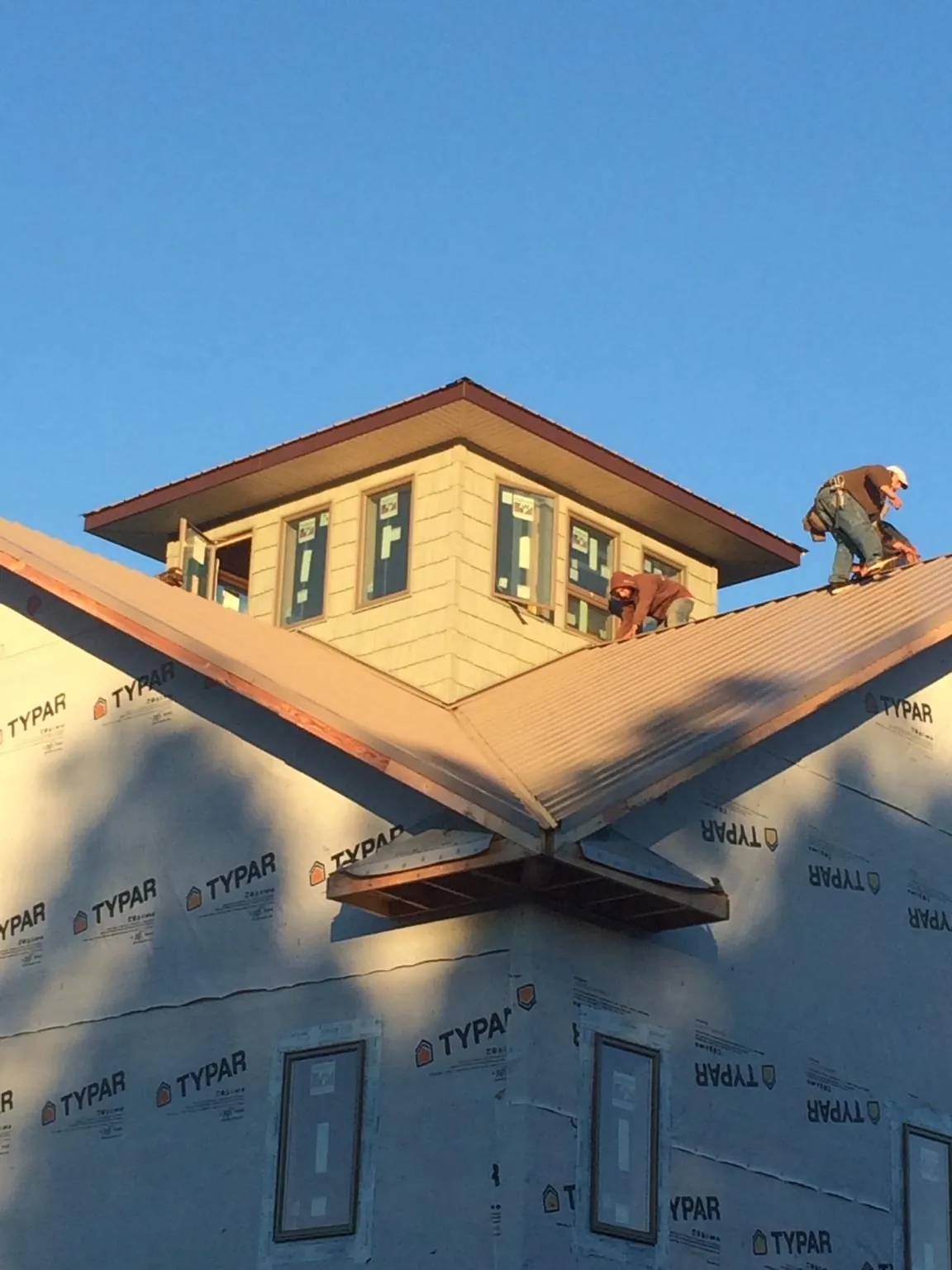 Roofers working around a rooftop cupola on a new metal roof at sunset — Roof Waterproofing in Tryon by Roofing Brothers